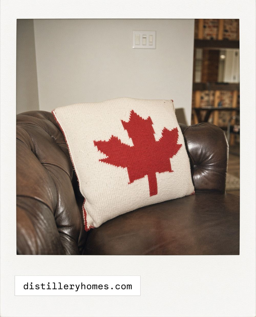 Brown leather chesterfield sofa with a knitted Canadian maple leaf pillow at 763 Monmouth Road